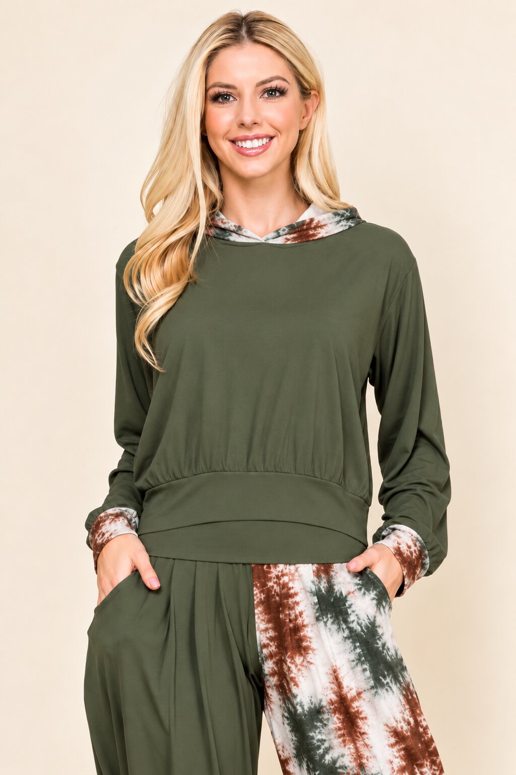 A woman modeling a two-piece lounge set consisting of an olive green long-sleeve top with a tie-dye patterned collar and cuffs, paired with matching olive green pants featuring a tie-dye patterned leg.